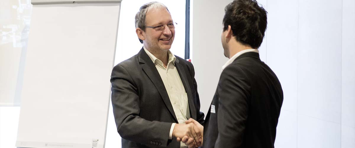 Dr. Schoeps und sein Auftraggeber geben sich die Hände nach erfolgreicher Präsentation